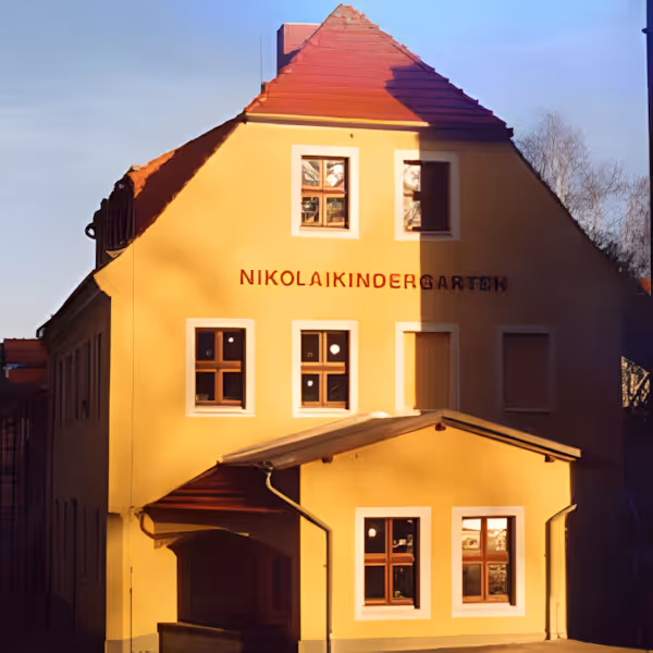 Gelbe Fassade des Kinderhauses Nikolaivorstadt mit dem Schriftzug Nikolaikindergarten über den Fenstern.